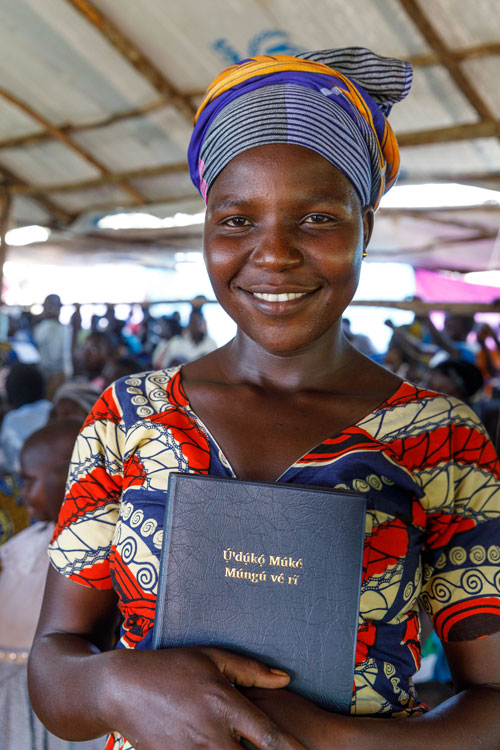 Uganda smiling woman hold up her new Bible